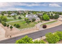 Expansive property featuring a two-story home with a wraparound porch and white fencing at 10170 E 151St Ct, Brighton, CO 80602