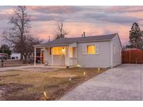 Charming single-story home with new gray siding, a covered porch, and a well-maintained front yard at dusk at 1161 S Perry St, Denver, CO 80219