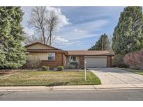 Charming brick home with a well-manicured front yard, mature trees, and an attached two-car garage at 8122 W Woodard Dr, Lakewood, CO 80227