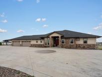 Expansive ranch home featuring stone accents and a large circular driveway for ample parking at 14025 Florence Ct, Brighton, CO 80602