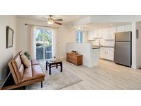 Bright living room with hardwood floors, a ceiling fan, and a sliding glass door to a balcony at 12486 W Nevada Pl # 106, Lakewood, CO 80228