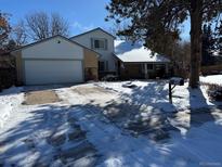 Two-story home with attached garage, covered porch, and snowy yard at 18360 E Ithaca Pl, Aurora, CO 80013