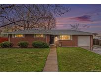 Charming brick ranch-style home with a well-manicured lawn and inviting walkway at dusk at 6613 Independence St, Arvada, CO 80004