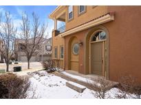 Inviting front entrance with arched doorway, covered porch, and well-maintained landscaping in a stucco home at 10127 Bluffmont Ln, Lone Tree, CO 80124