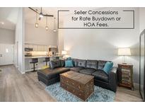 Bright open concept living room featuring a kitchen bar, sleek ceiling fan, and comfortable leather sectional at 2279 E 129Th Ave, Thornton, CO 80241