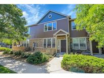 Beautiful townhouse featuring stone accents, a well-maintained lawn, and inviting curb appeal on a sunny day at 12793 Leyden St # D, Thornton, CO 80602