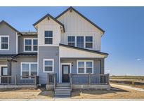 Charming two-story townhouse with gray and white siding, a cozy front porch, and modern architectural details at 6562 Arbor Blvd # 1, Thornton, CO 80602