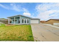Charming home featuring a well-maintained lawn, covered porch, and an attached two-car garage at 243 Cherokee Ct, Brighton, CO 80603