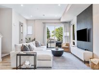 Bright living room featuring a comfortable sectional sofa, modern decor, and sliding glass doors to balcony at 9052 Harlan St, Westminster, CO 80031