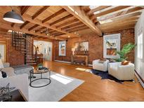 Stunning living room features exposed brick walls, wood-beamed ceilings, and a modern spiral staircase at 1125 E Kentucky Ave, Denver, CO 80209