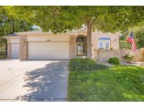 Charming brick home with a well-manicured lawn, mature tree, and American flag for a welcoming curb appeal at 12705 Kalamath Ct, Westminster, CO 80234