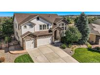 Two-story house with stone accents, three-car garage, and landscaped yard at 6017 Merchant Pl, Parker, CO 80134