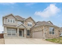 Charming two-story home featuring a stone facade, covered porch, and attached two car garage in a suburban neighborhood at 1445 Colebrook Ct, Castle Rock, CO 80109