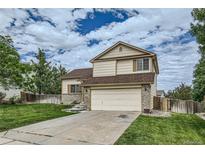 Two story tan house with beige brick siding, a two car garage, and a well maintained lawn at 9544 Josephine St, Thornton, CO 80229