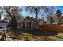 Charming gray home featuring a cozy front porch with wooden pillars and a well-maintained lawn at 6240 W 24Th Ave, Edgewater, CO 80214