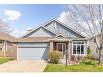 Charming single-Gathering home featuring blue siding, brick accents, and an attached two-car garage at 2590 S Independence St, Lakewood, CO 80227