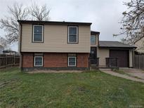 Charming two-story home featuring tan siding, brick accents, and an attached one-car garage at 220 Mckinley Dr, Bennett, CO 80102