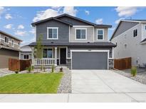 Inviting two-story home with gray accents, stone details, and a well-maintained lawn at 45927 Wood Thrush Ave, Bennett, CO 80102