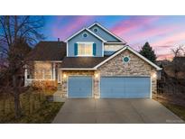 Charming two-story home featuring a stone and blue facade, three-car garage, and landscaped front yard at 5604 S Shawnee St, Aurora, CO 80015