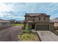 Charming two-story home featuring a two-car garage, quaint front porch, and landscaped front yard at 2303 Monte Vista St, Fort Lupton, CO 80621