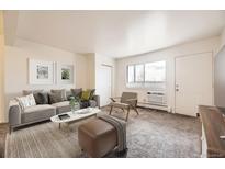Bright living room featuring a plush sofa, modern decor, and natural light streaming through a large window at 5995 W Hampden Ave # 8C, Denver, CO 80227