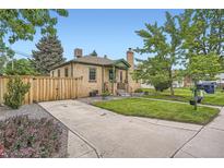 Charming brick home featuring a lush lawn, concrete driveway, and a wooden fence for added privacy at 5704 Ammons St, Arvada, CO 80002