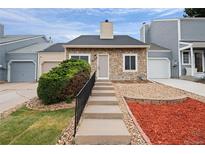 Charming townhome featuring a stone facade, well-manicured landscaping, and a welcoming front entrance at 19616 E Milan Cir, Aurora, CO 80013