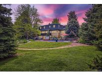 Expansive backyard featuring a pool, lush lawn, mature trees and beautiful landscaping at 6451 Crestbrook Dr, Morrison, CO 80465
