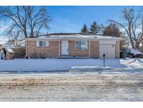 Brick ranch home with attached garage and snowy front yard at 2002 Truda Dr, Northglenn, CO 80233