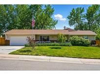 Charming ranch-style home featuring a lush front lawn and beautiful landscaping with mature trees and an American flag at 3570 E Arapahoe Pl, Centennial, CO 80122