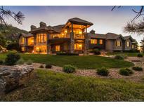 Luxury home with stone accents, expansive lawn, and mountain views at dusk at 9977 Elkhorn St, Littleton, CO 80127