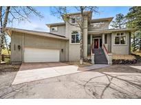 Contemporary home showcasing a front entrance with red accents and a spacious two-car garage at 19640 Four Winds Way, Monument, CO 80132