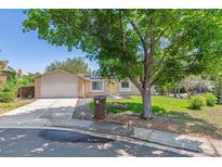 Charming brick and siding home with an attached garage, lush lawn, and a large shade tree in the front yard at 3253 S Kalispell St, Aurora, CO 80013