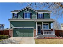 Inviting two-story home featuring an attached two-car garage, well-manicured lawn, and classic architectural details at 10041 Dillon Cir, Commerce City, CO 80022
