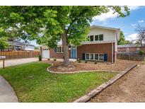 Charming two-story brick home with a well-manicured lawn, mature tree, and a bright blue front door at 1011 Yeager Dr, Longmont, CO 80501