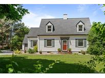 Charming two-story home boasts a manicured lawn, dormer windows, and a striking red front door at 1033 Estes St, Lakewood, CO 80215