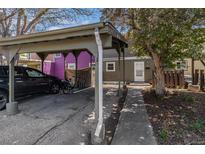 Charming home exterior with carport, sidewalk, and freshly painted purple accent house in the background at 709 Arrow Ct, Lafayette, CO 80026