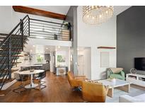 Inviting living room featuring high ceilings, modern chandelier, wood floors, and open staircase to the second floor at 505 Detroit St, Denver, CO 80206