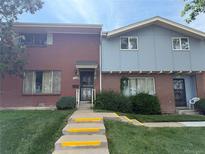 A symmetrical townhome featuring a blend of brick and siding, complemented by a well-maintained lawn and walkway at 8779 Santa Fe Dr, Thornton, CO 80260