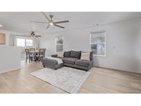 Bright living room with hardwood floors, a ceiling fan, and a comfortable gray sofa at 649 Mockingbird St, Brighton, CO 80601