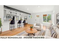 Bright open-concept living room flows into a modern kitchen with a breakfast bar and hardwood floors at 4701 E Jewell Ave, Denver, CO 80222