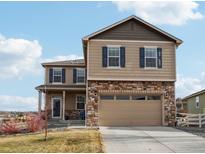 Two-story home featuring a stone facade, two-car garage, and blue shutters against a beautiful blue sky at 2042 Shadow Creek Dr, Castle Rock, CO 80104