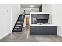 Modern kitchen features sleek gray cabinetry, stainless steel appliances, and concrete floors at 1601 Park Ave # 110, Denver, CO 80218