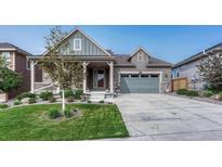 Charming home with a welcoming porch, well-manicured lawn, and two car garage for a lovely curb appeal at 6930 Hyland Hills St, Castle Pines, CO 80108