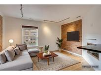 Virtually staged living room featuring exposed brick, hardwood floors, and modern furniture at 2306 Glenarm Pl # 206, Denver, CO 80205