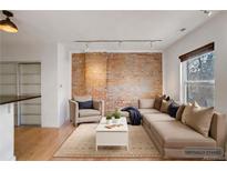 Virtually staged living room with exposed brick, hardwood floors, and sectional sofa at 2306 Glenarm Pl # 206, Denver, CO 80205