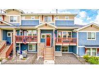 Inviting blue townhome featuring stone accents, red door and trim, and a cozy, railed balcony at 619 Brennan Cir, Erie, CO 80516