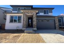 Two-story home with gray siding, stone accents, and a two-car garage at 9173 Truckee Ct, Commerce City, CO 80022