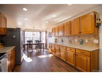 Bright kitchen features wood floors, wood cabinets, stainless steel appliances, and a breakfast nook at 1128 S Duquesne Cir, Aurora, CO 80018