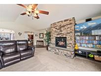 Cozy living room features a stone fireplace, plush carpeting, and a ceiling fan at 1128 S Duquesne Cir, Aurora, CO 80018